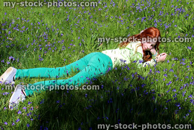 Stock image of girl with long red hair in woodland of bluebell flowers
