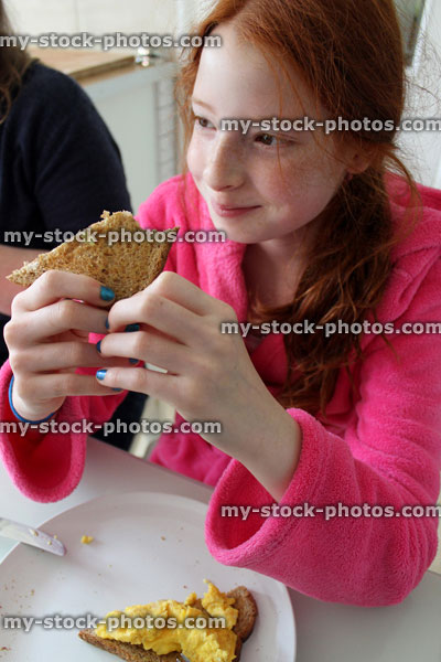 Stock image of young girl eating healthy breakfast in pink dressing gown