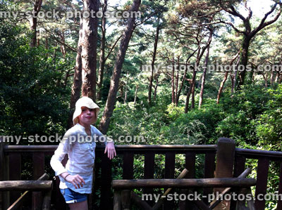 Stock image of young girl in woodland gardens with pine trees