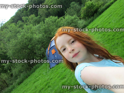 Stock image of girl on camping site with tent in background, selfie