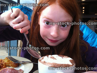 Stock image of girl drinking frothy hot chocolate with fried breakfast