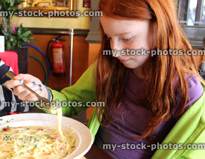 Stock image of girl eating spaghetti carbonara pasta in italian restaurant