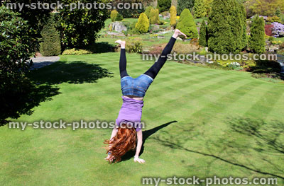 Stock image of young girl doing cartwheels in large garden
