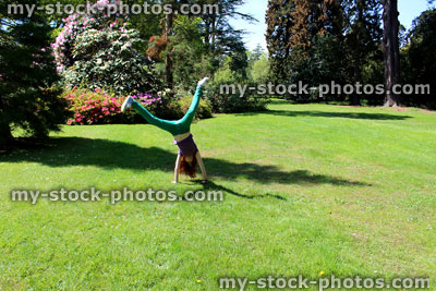 Stock image of girl doing cartwheel / handstand on sunny garden lawn