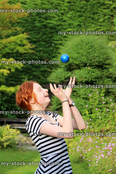 Stock image of girl catching ball with hands in garden, playing catch game