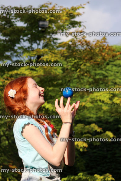 Stock image of girl catching ball with hands in garden, playing catch game
