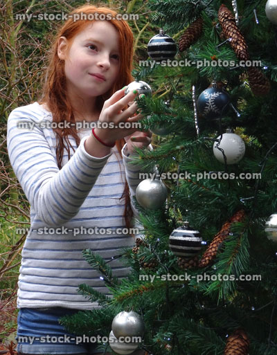 Stock image of girl decorating Christmas tree in garden with baubles