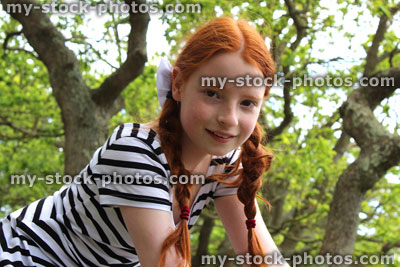 Stock image of tomboy girl sitting in branches of oak tree in woodland