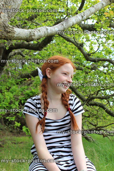 Stock image of tomboy girl sitting on branch of oak tree in woodland