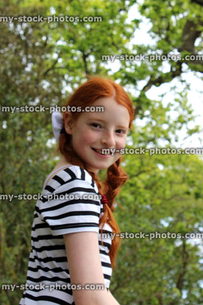 Stock image of tomboy girl sitting in branches of oak tree in woodland