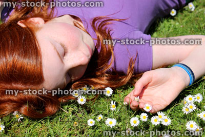 Stock image of girl with red hair lying in field of daisies, flowers