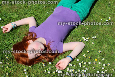 Stock image of girl with red hair lying asleep in daisy field / meadow