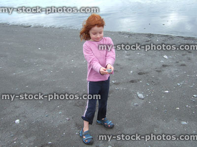 Stock image of little girl on a dark sand beach