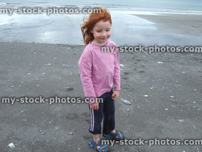 Stock image of little girl on a dark sand beach