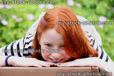 Stock image of girl lying down on wooden bench, looking forwards