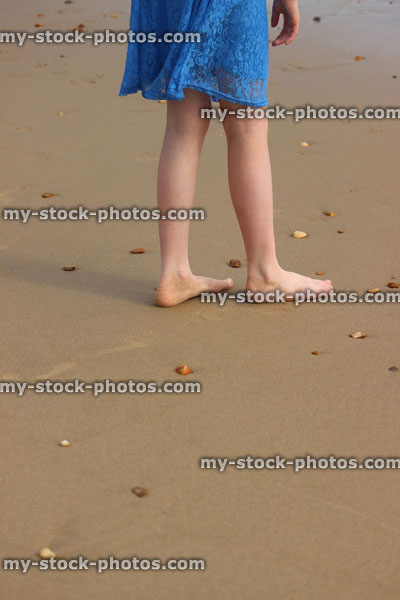 Stock image of girl walking barefoot on beach / seaside sand, by sea waves