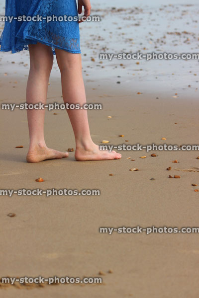 Stock image of girl walking barefoot on beach / seaside sand, by sea waves