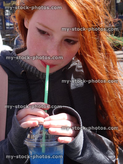 Stock image of girl drinking sugary, blue raspberry flavoured slushie drink