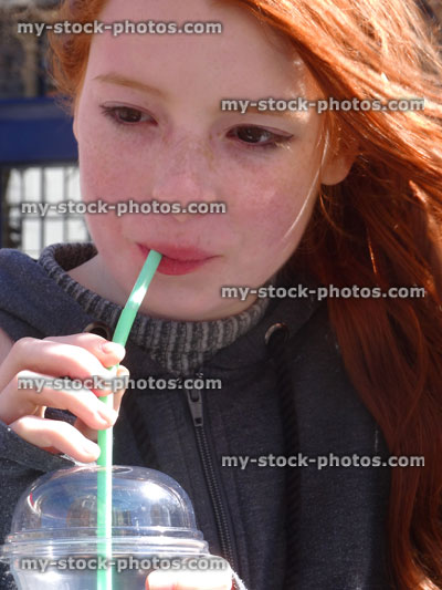 Stock image of girl drinking unhealthy sugary soft drink with straw