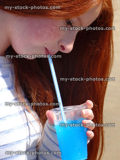 Stock image of girl drinking blue iced slushie drink with straw