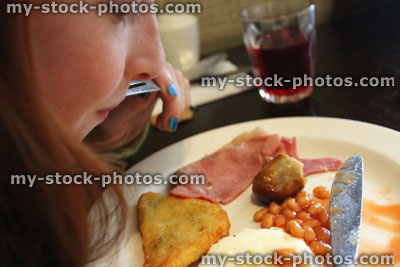 Stock image of young girl eating a full English fried breakfast