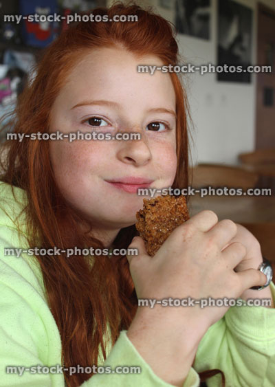 Stock image of girl eating flapjack cake biscuit made with oats