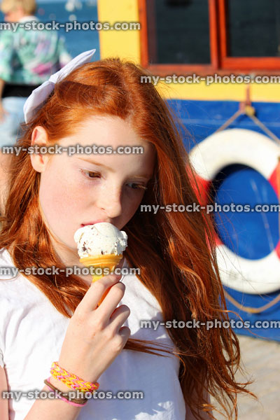 Stock image of girl on seaside holiday, eating ice cream cone / vanilla icecream