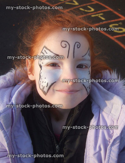 Stock image of little girl with butterfly face paint in playground