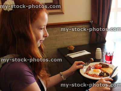 Stock image of girl eating full English fried breakfast in hotel restaurant