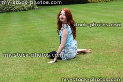 Stock image of young girl sitting on lawn grass in garden