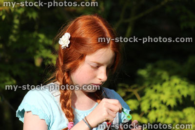 Stock image of girl trying to blow bubbles in garden sunshine