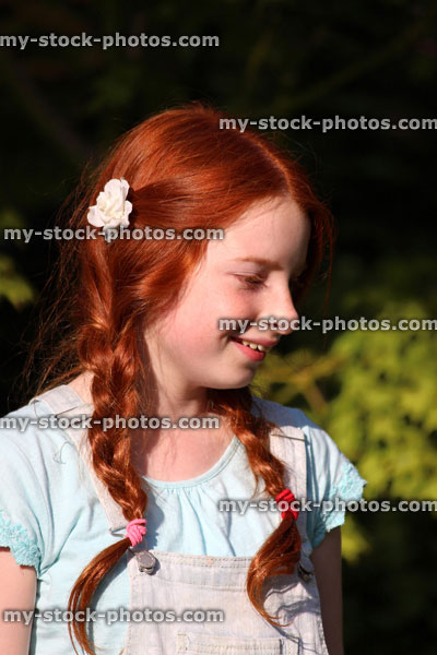 Stock image of young girl with red hair, long pigtails, plaits, braided hair