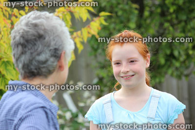 Stock image of young girl playing in garden with grandmother / granddaughter