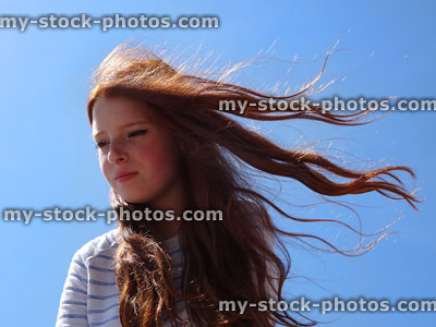 Stock image of girl with long hair against sky, blowing in wind