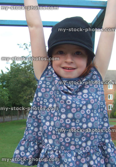Stock image of girl hanging from monkey bars