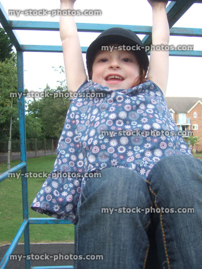 Stock image of girl hanging from monkey bars