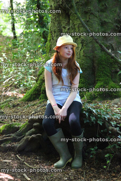 Stock image of girl in woodland forest, straw hat, daydreaming, looking, sitting on log