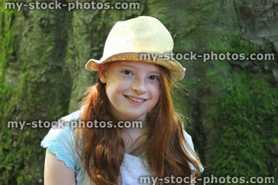 Stock image of girl in woodland forest, straw hat, sitting, looking, daydreaming, tree trunk