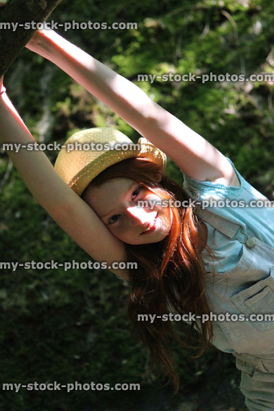 Stock image of girl in woodland forest, straw hat, standing, posing, hanging from branch