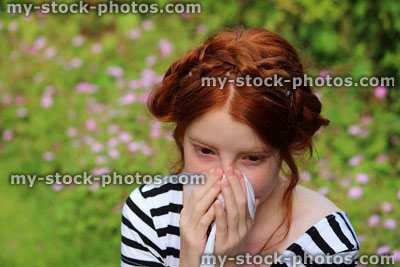 Stock image of girl in flower gardens with hayfever, blowing nose, sneezing, allergies