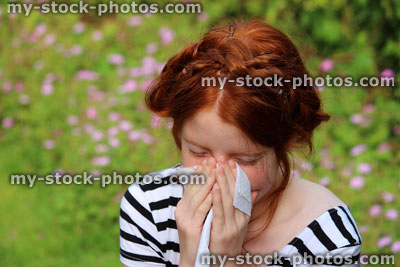 Stock image of girl in flower gardens with hayfever, blowing nose, sneezing, allergies