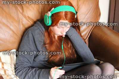 Stock image of girl wearing headphones and playing on iPad tablet computer