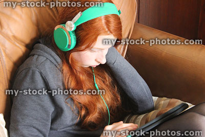 Stock image of girl listening to music on tablet computer, wearing headphones