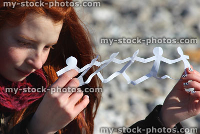 Stock image of girl looking at people paperchain, holding in hands