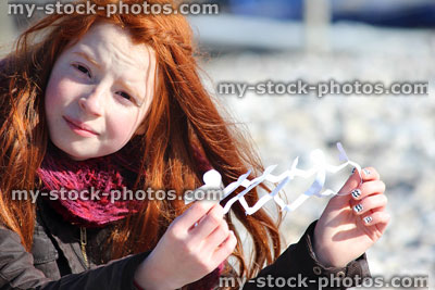 Stock image of girl on beach holding up white people paperchain