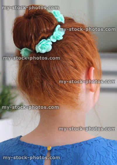 Stock image of girl with red hair in bun, looking in mirror, rear view