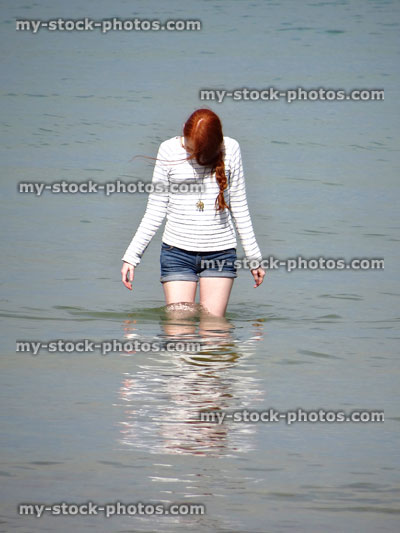 Stock image of girl paddling in sea, reflection in water ripples