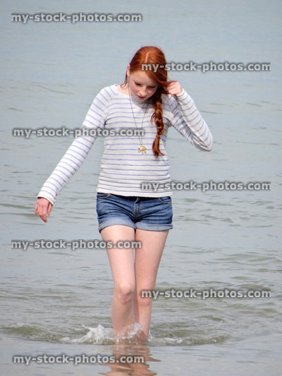Stock image of girl paddling in sea wearing denim jean shorts