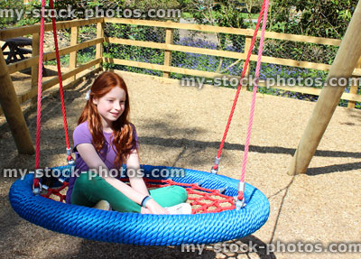 Stock image of young child in woodland playground, on cradle swing