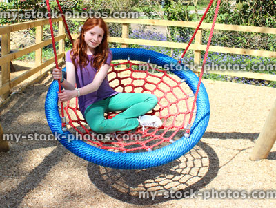 Stock image of young child playing in woodland playground, on cradle swing